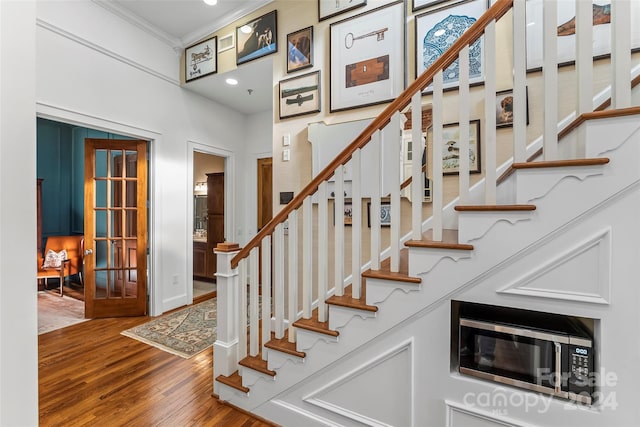 stairs featuring baseboards, wood finished floors, recessed lighting, and ornamental molding