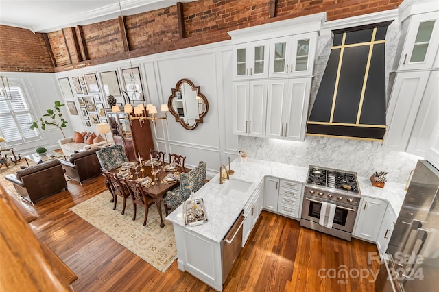 kitchen with high end stainless steel range oven, a sink, dark wood finished floors, and a decorative wall