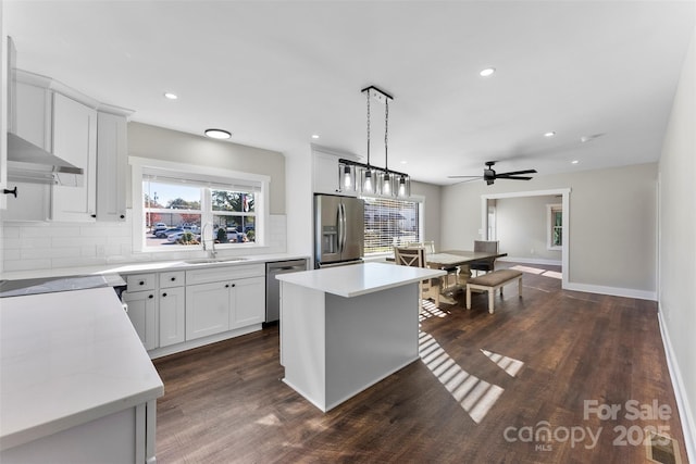 kitchen featuring pendant lighting, backsplash, a center island, and stainless steel appliances