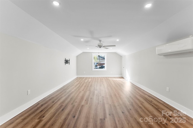 additional living space featuring an AC wall unit, ceiling fan, hardwood / wood-style floors, and lofted ceiling