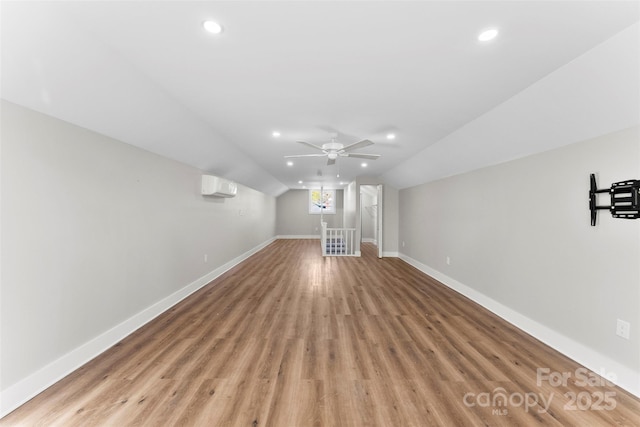 additional living space with ceiling fan, light wood-type flooring, lofted ceiling, and a wall mounted AC