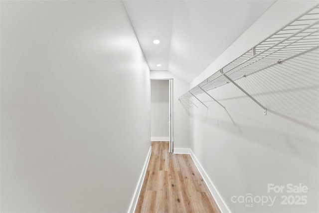 walk in closet featuring light wood-type flooring and lofted ceiling