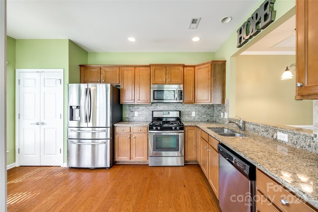 kitchen with crown molding, sink, light hardwood / wood-style flooring, and stainless steel appliances