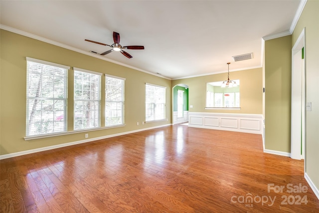 unfurnished living room with ornamental molding, a wealth of natural light, light wood-type flooring, and ceiling fan with notable chandelier