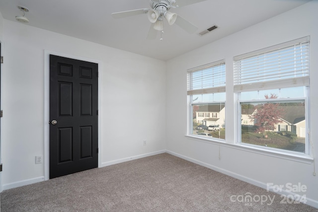 empty room with ceiling fan, carpet flooring, and a wealth of natural light