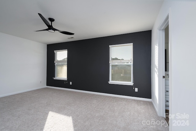 carpeted spare room featuring ceiling fan and a healthy amount of sunlight