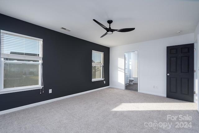 interior space with light carpet, ceiling fan, and ensuite bath