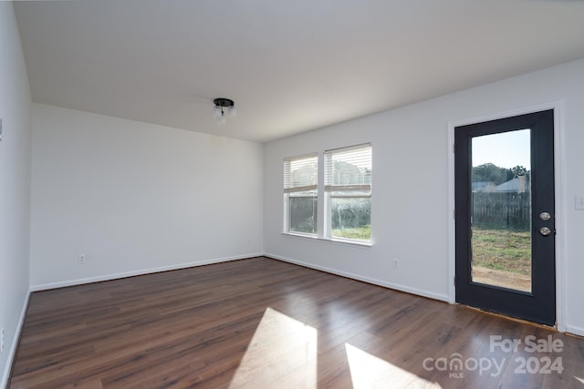 empty room with dark hardwood / wood-style floors and plenty of natural light