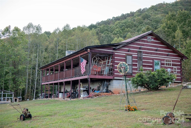 back of property featuring a deck with mountain view and a lawn