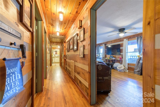 corridor with wooden walls and hardwood / wood-style floors