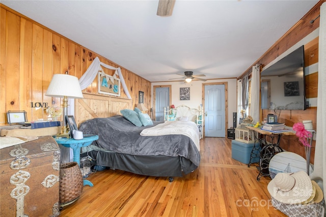 bedroom with crown molding, light hardwood / wood-style flooring, ceiling fan, and wood walls