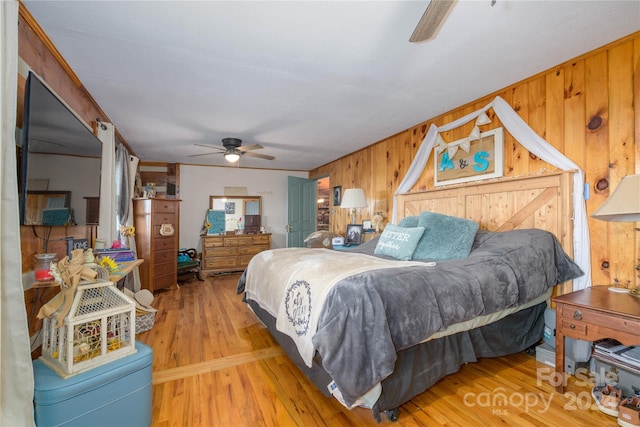 bedroom with hardwood / wood-style floors, wooden walls, and ceiling fan