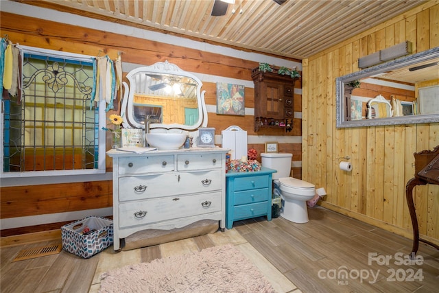 bathroom featuring wood ceiling, toilet, hardwood / wood-style floors, vanity, and wood walls