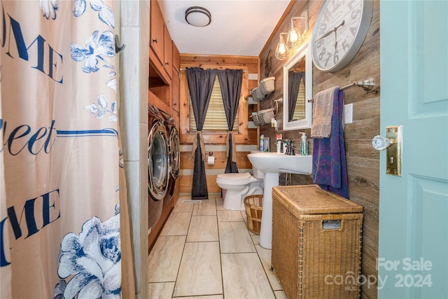 bathroom with washer / dryer, sink, toilet, wooden walls, and tile patterned flooring