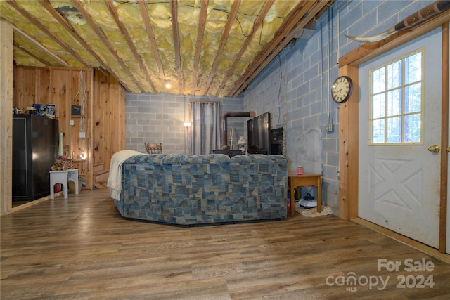 living room featuring lofted ceiling, hardwood / wood-style floors, and wooden walls