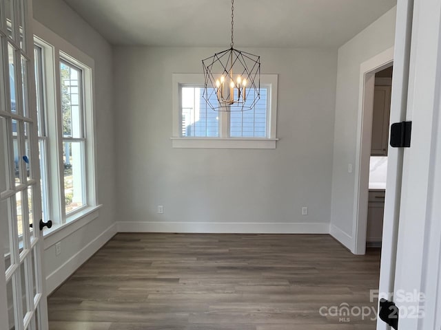 unfurnished dining area with hardwood / wood-style floors and a notable chandelier