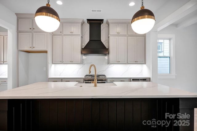 kitchen with light stone counters, custom range hood, and pendant lighting