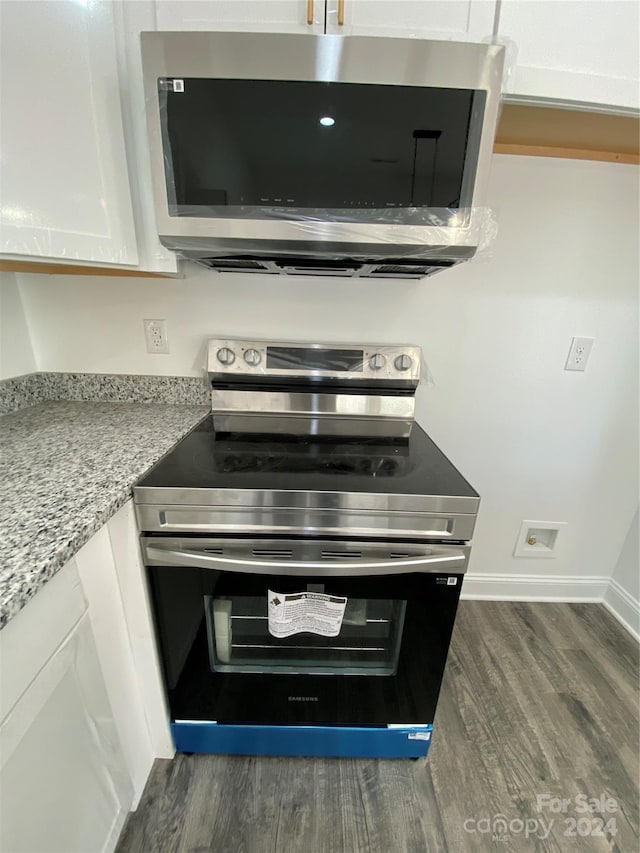 kitchen featuring white cabinetry, stainless steel appliances, light stone countertops, and dark hardwood / wood-style flooring