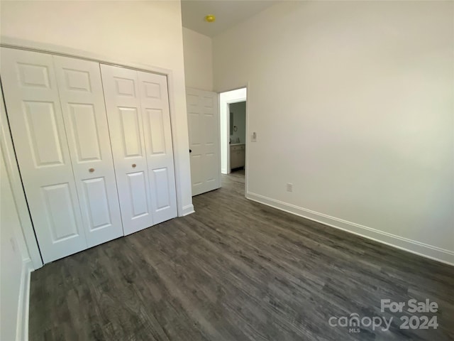 unfurnished bedroom featuring a closet, a high ceiling, and dark hardwood / wood-style floors