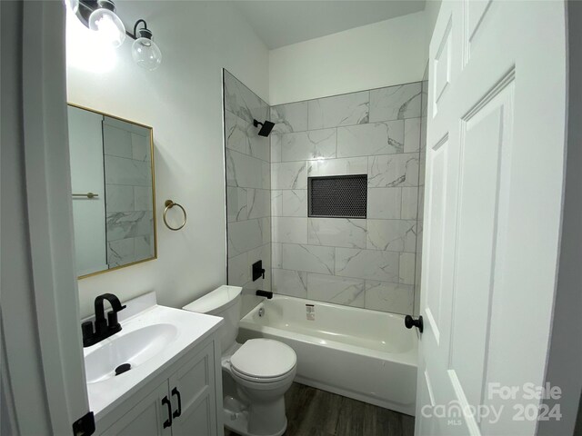 full bathroom with vanity, tiled shower / bath combo, hardwood / wood-style flooring, and toilet