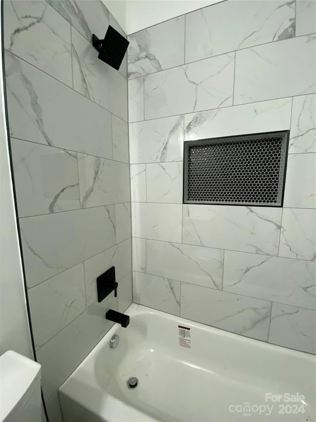 bathroom with toilet and tiled shower / bath combo