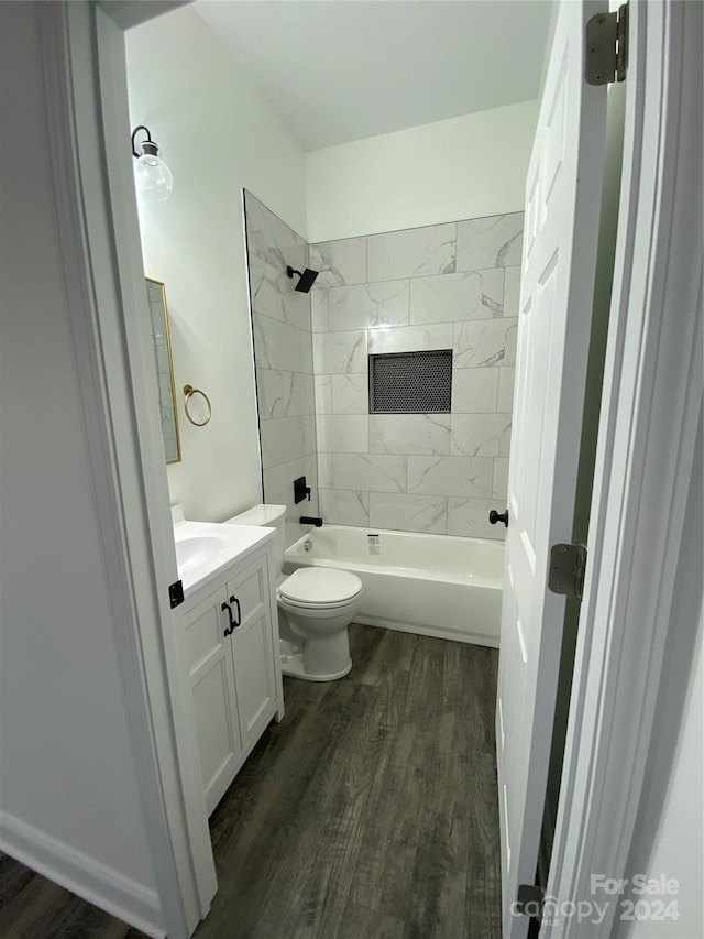 full bathroom featuring tiled shower / bath, vanity, hardwood / wood-style floors, and toilet