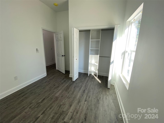 unfurnished bedroom with dark hardwood / wood-style floors and a closet