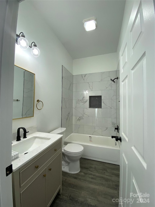 full bathroom with vanity, toilet, hardwood / wood-style floors, and tiled shower / bath