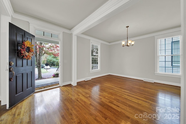 foyer featuring beam ceiling, crown molding, hardwood / wood-style flooring, and an inviting chandelier