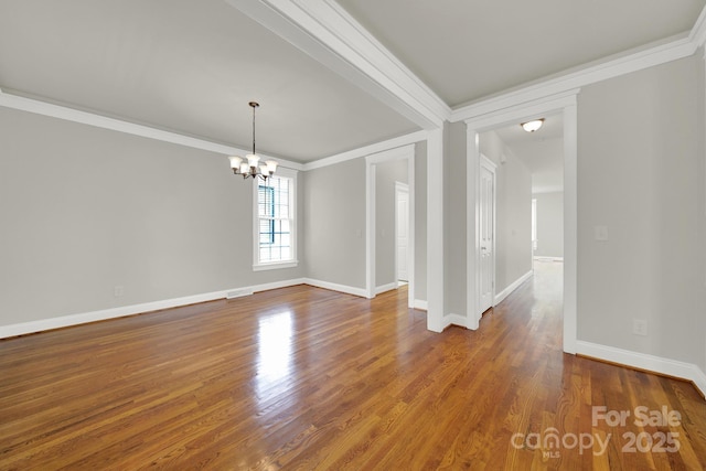 empty room featuring an inviting chandelier, wood-type flooring, and ornamental molding