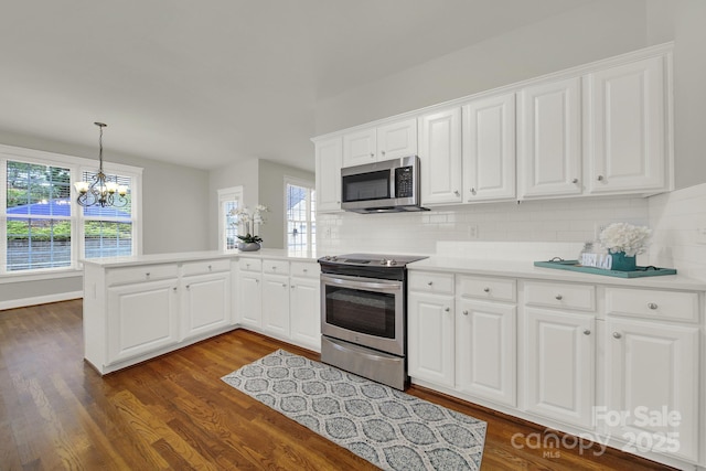 kitchen with kitchen peninsula, a chandelier, decorative backsplash, white cabinets, and appliances with stainless steel finishes