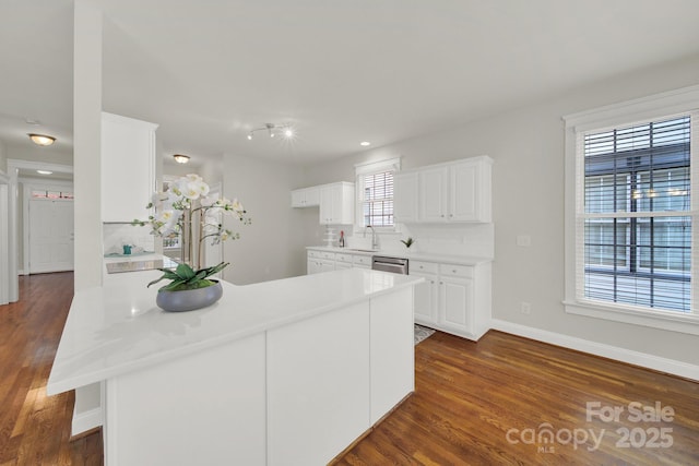 kitchen with dishwasher, white cabinets, sink, tasteful backsplash, and kitchen peninsula