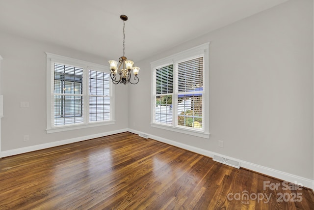 unfurnished dining area featuring dark hardwood / wood-style flooring and a notable chandelier