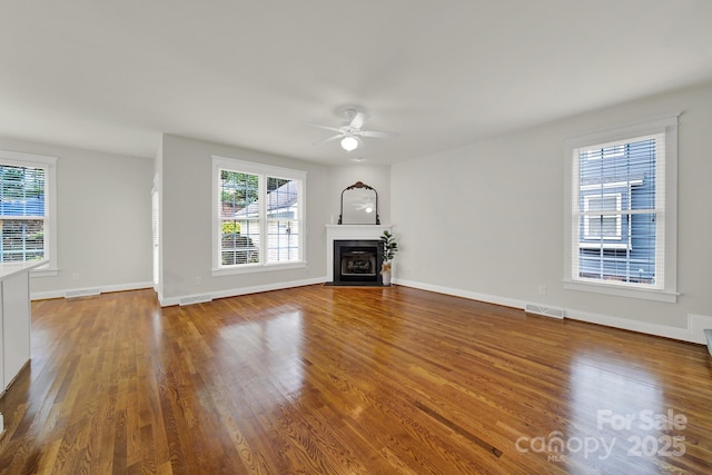 unfurnished living room featuring ceiling fan, plenty of natural light, and wood-type flooring