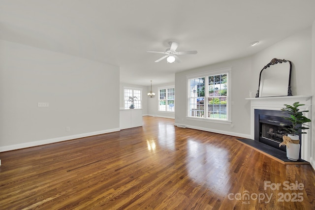 unfurnished living room featuring dark hardwood / wood-style flooring and ceiling fan with notable chandelier