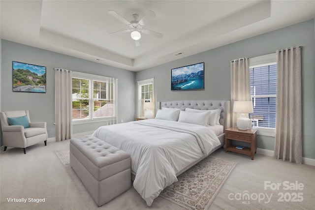 bedroom featuring light carpet, a tray ceiling, and ceiling fan