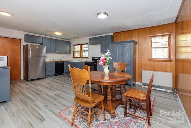 dining space with sink, wooden walls, heating unit, and light hardwood / wood-style floors