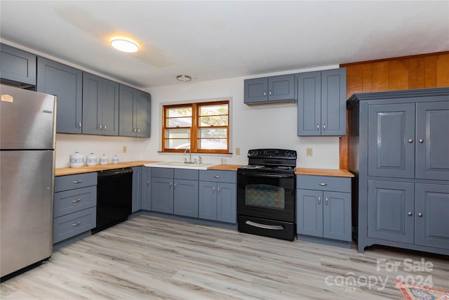 kitchen featuring sink, black appliances, light wood-type flooring, and wood counters