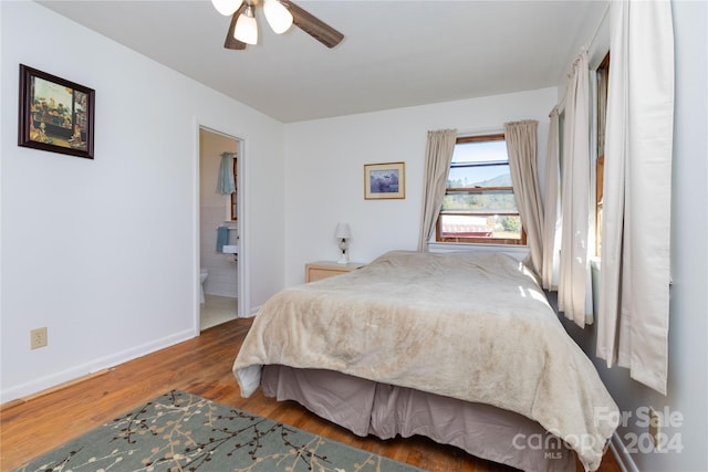 bedroom featuring dark hardwood / wood-style flooring, ensuite bath, and ceiling fan