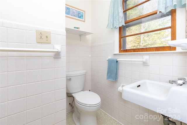 bathroom featuring tile walls, sink, and toilet