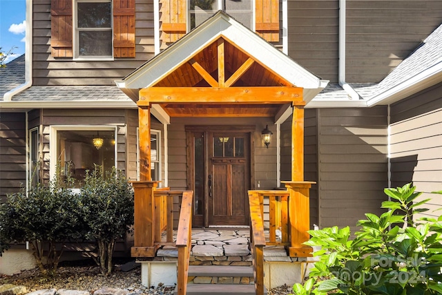 property entrance with a shingled roof and covered porch
