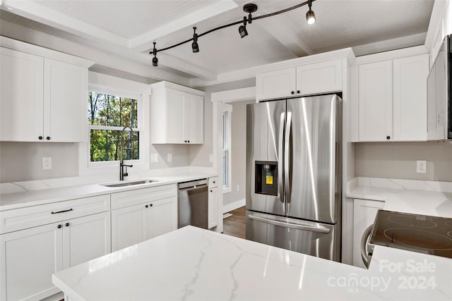 kitchen featuring a sink, beamed ceiling, white cabinets, appliances with stainless steel finishes, and light stone countertops