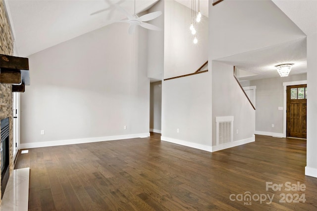 unfurnished living room featuring a stone fireplace, dark hardwood / wood-style floors, a textured ceiling, high vaulted ceiling, and ceiling fan