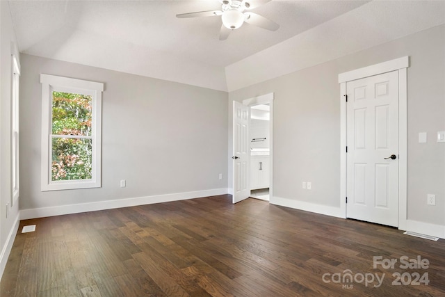 empty room featuring a ceiling fan, baseboards, vaulted ceiling, and dark wood finished floors