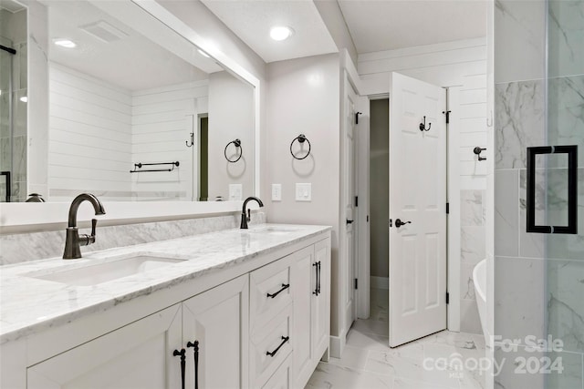 full bath featuring double vanity, marble finish floor, a sink, and a freestanding bath