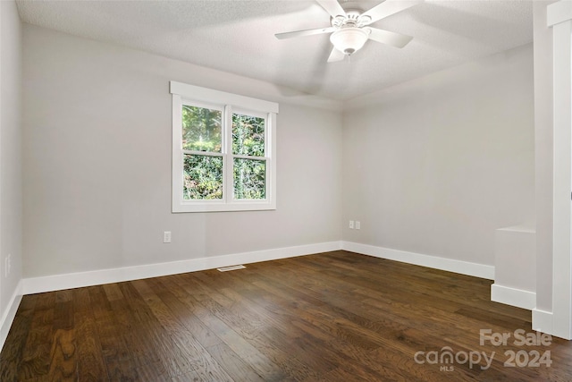 empty room featuring ceiling fan, a textured ceiling, and dark hardwood / wood-style flooring