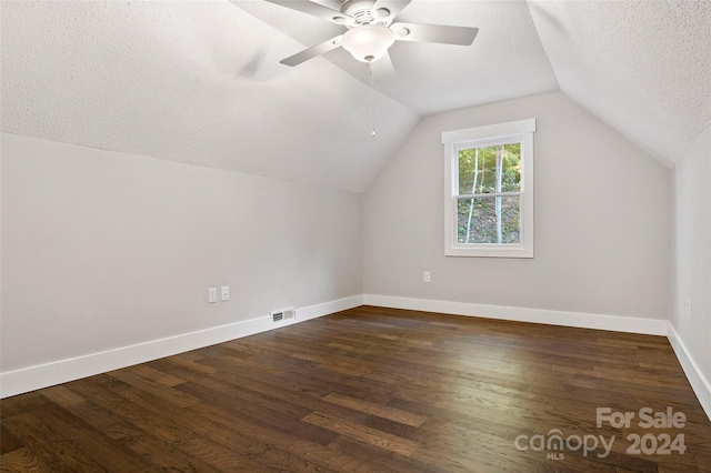 bonus room with lofted ceiling, a textured ceiling, dark hardwood / wood-style floors, and ceiling fan