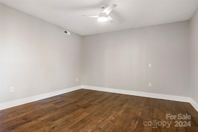 empty room featuring dark wood-style floors, baseboards, a ceiling fan, and visible vents