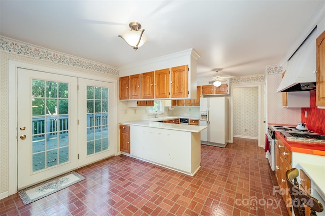 kitchen with kitchen peninsula, ceiling fan, white fridge with ice dispenser, crown molding, and sink