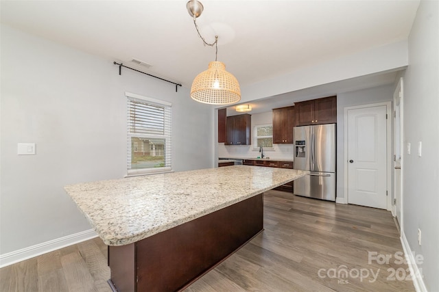 kitchen with stainless steel fridge with ice dispenser, a center island, decorative light fixtures, and wood-type flooring